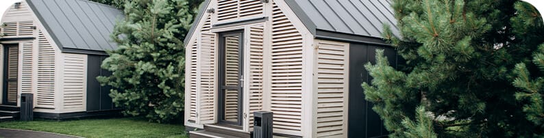 Two separated ADUs approximately 10ft by 10ft, with open glass doors and trees on the sides of them.