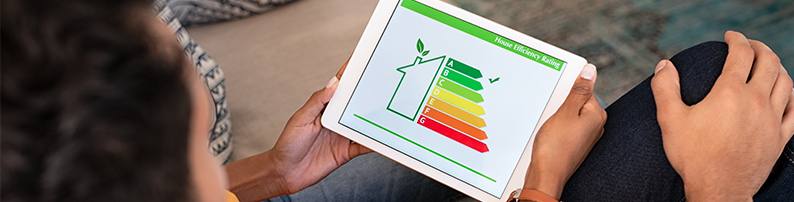 Person holding digital tablet which depicts a house and colored bars showing efficiency